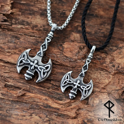 Two Viking-style double-headed axe pendants on chains, displayed on a rustic wood background. One pendant is silver with a silver chain, and the other is silver with a black cord.